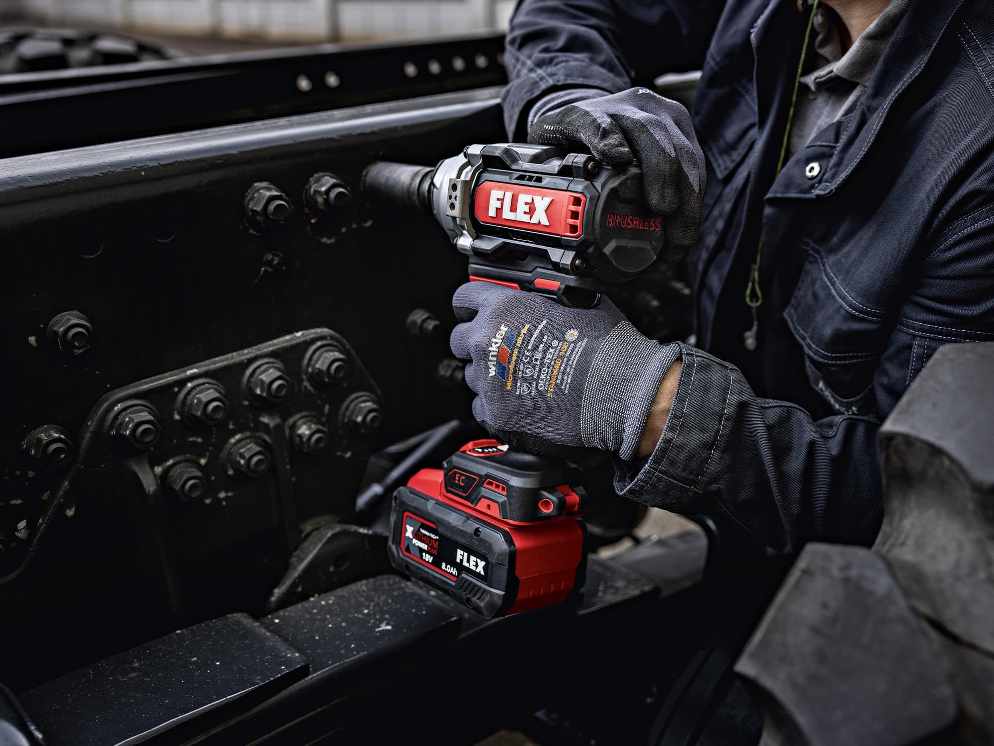 A screw is tightened on a truck using a FLEX cordless impact wrench.