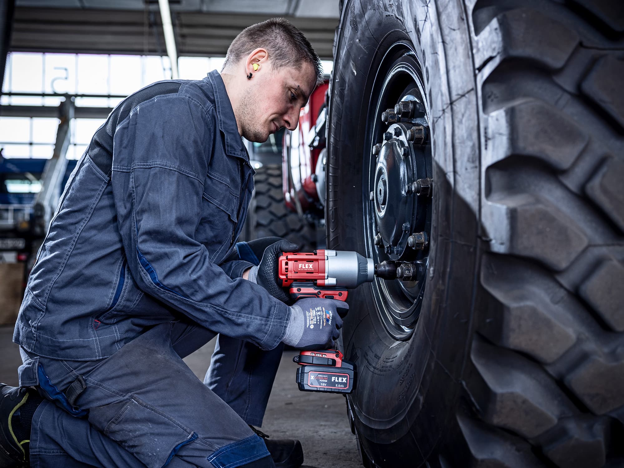 Mechanic tightens bolts on a truck tyre using a FLEX impact wrench