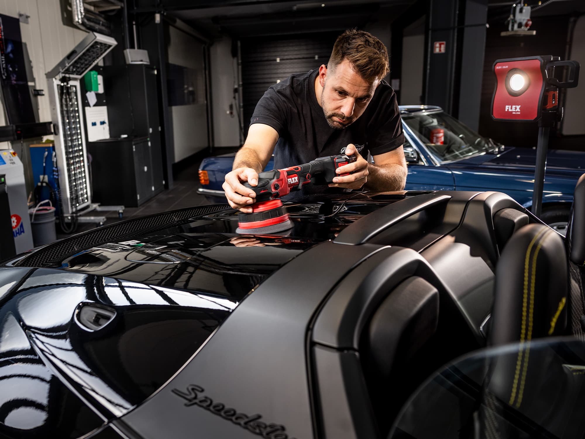 A detailer polishes a black car with a cordless polisher from FLEX.