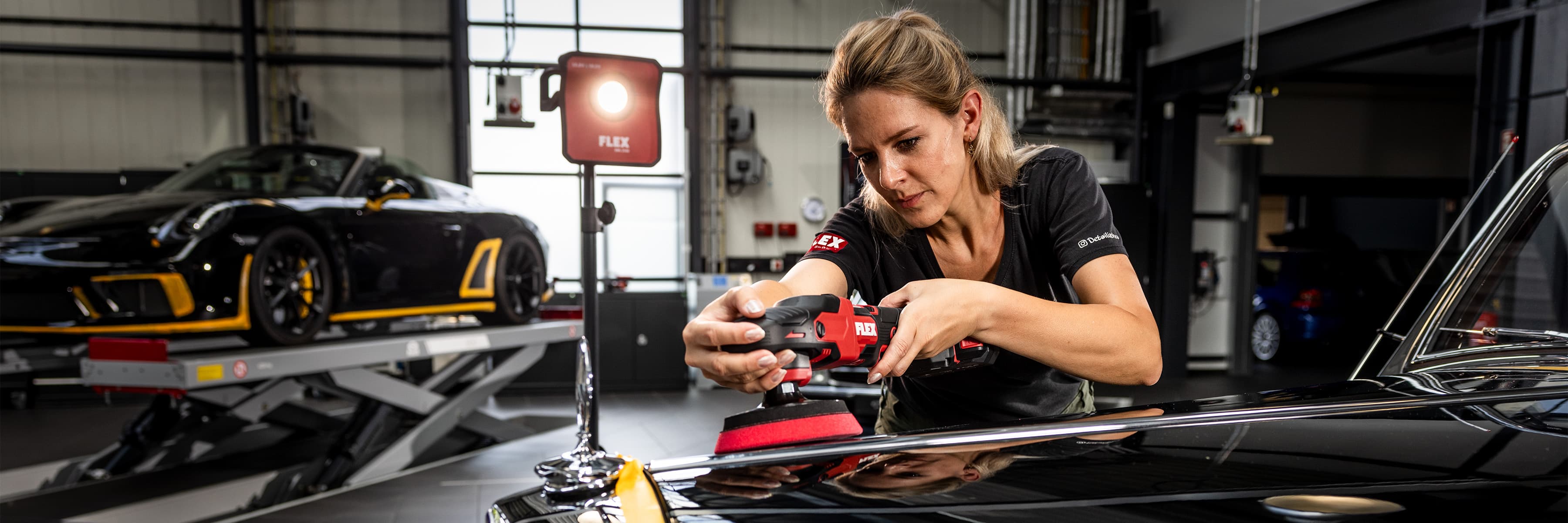 A vehicle detailer polishes a car with a FLEX cordless polisher.