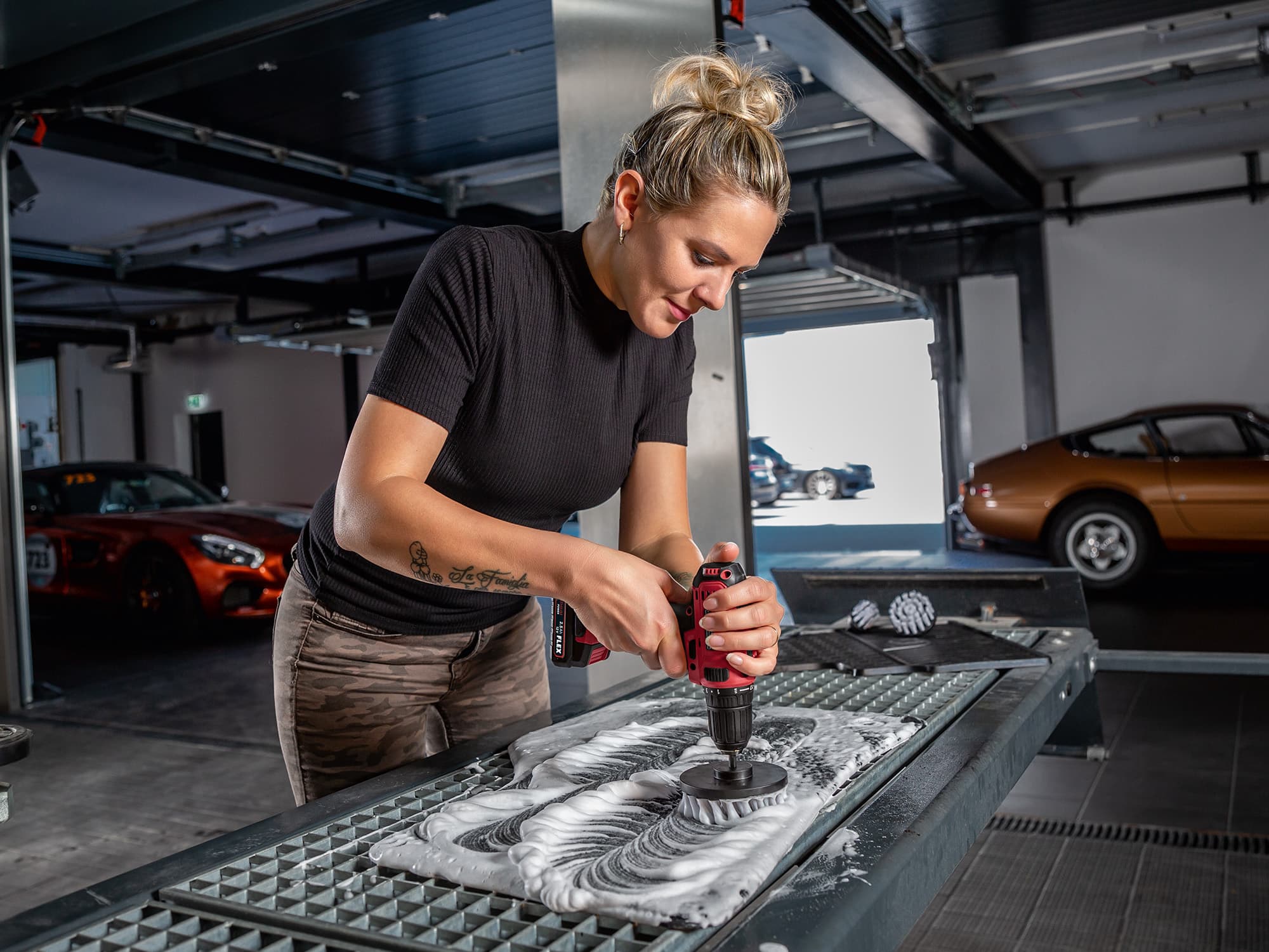 A car floor mat is cleaned using a FLEX screwdriver and the brush set.