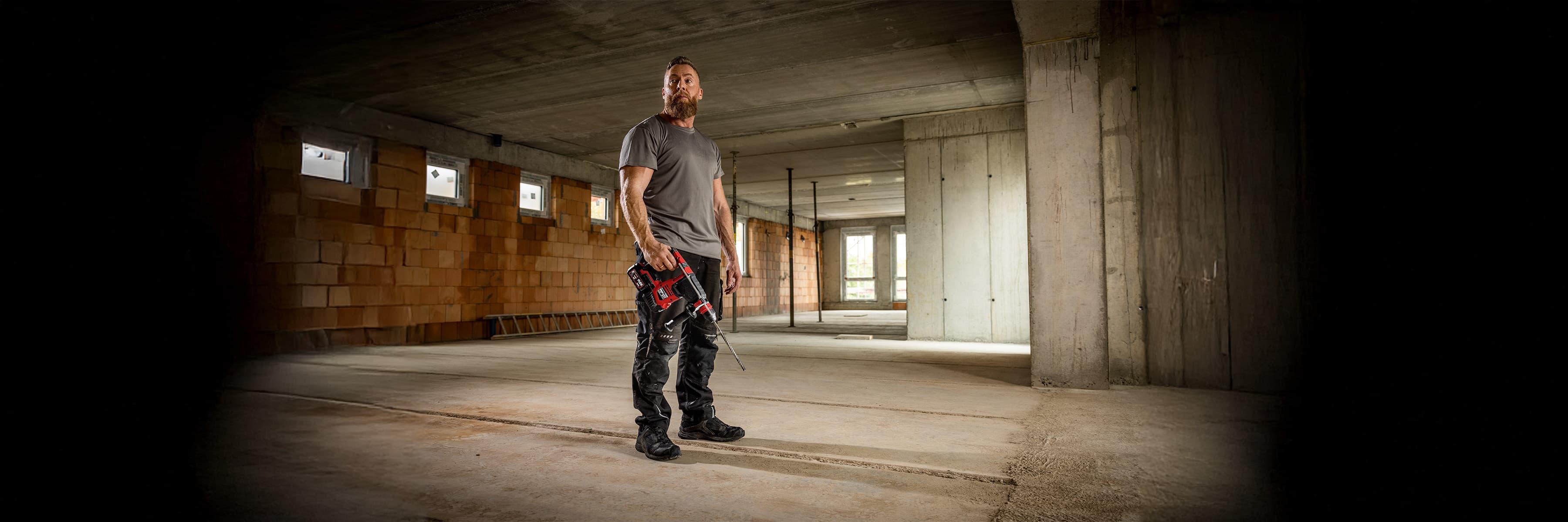 Craftsman standing on a construction site with a cordless hammer drill